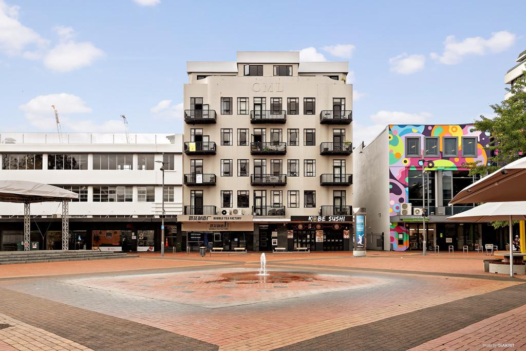 Street-level view of the fountain, open paving and shopfronts facing Garden Place